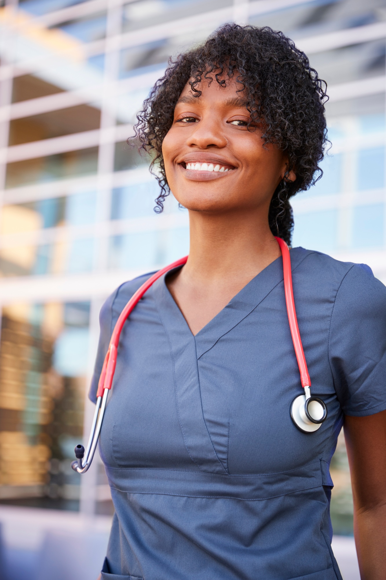 Smiling black female healthcare worker outdoors, vertical